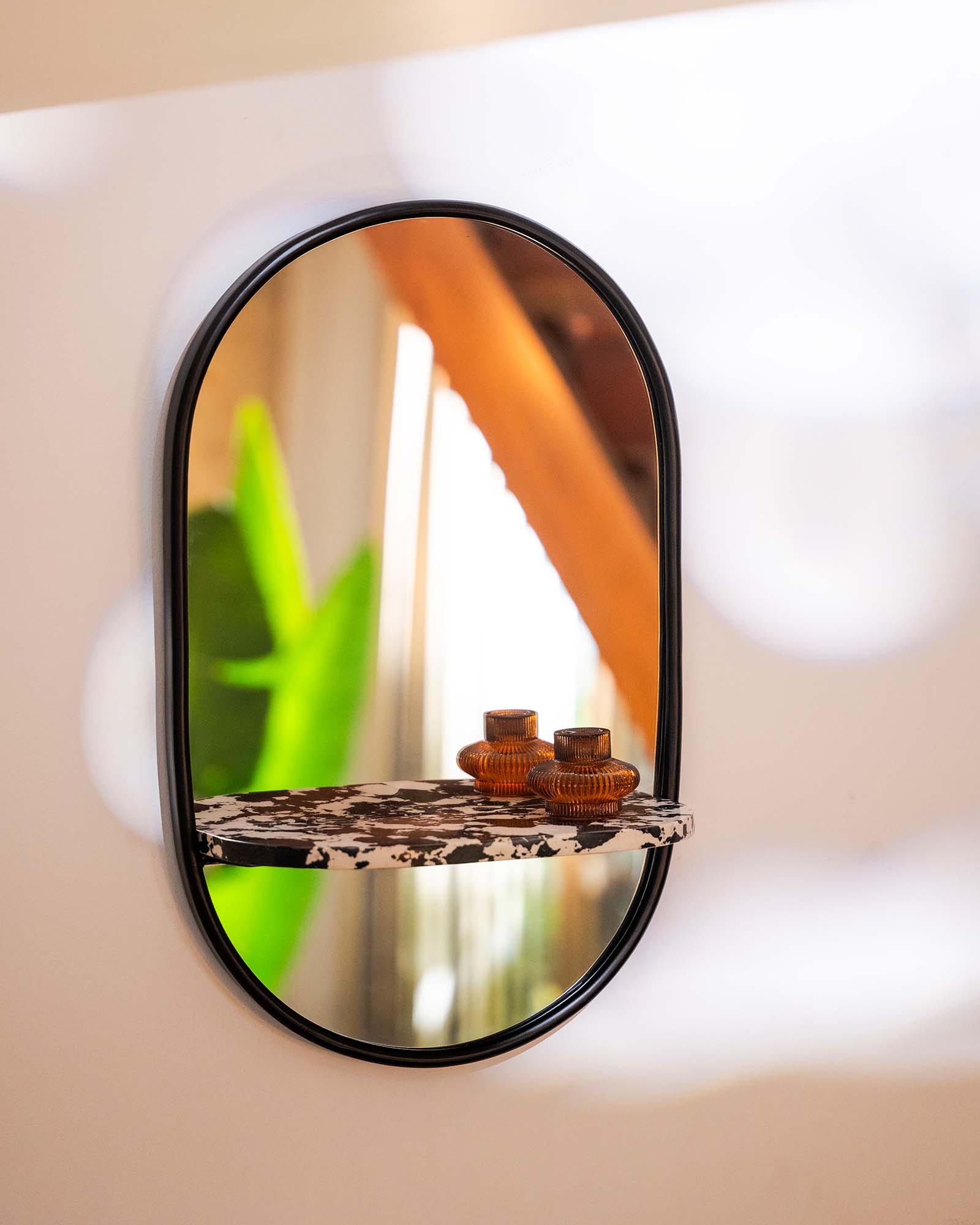Modern wall mirror with built-in shelf for décor and essentials.